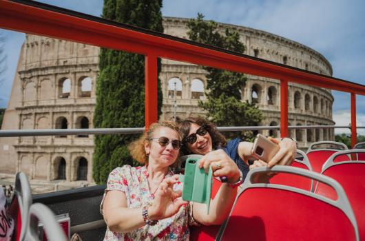 Due persone scattano selfie davanti al Colosseo.